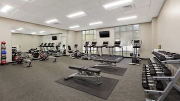 Ein Fitnessstudio mit Laufbändern, Kraftgeräten und Kurzhanteln.