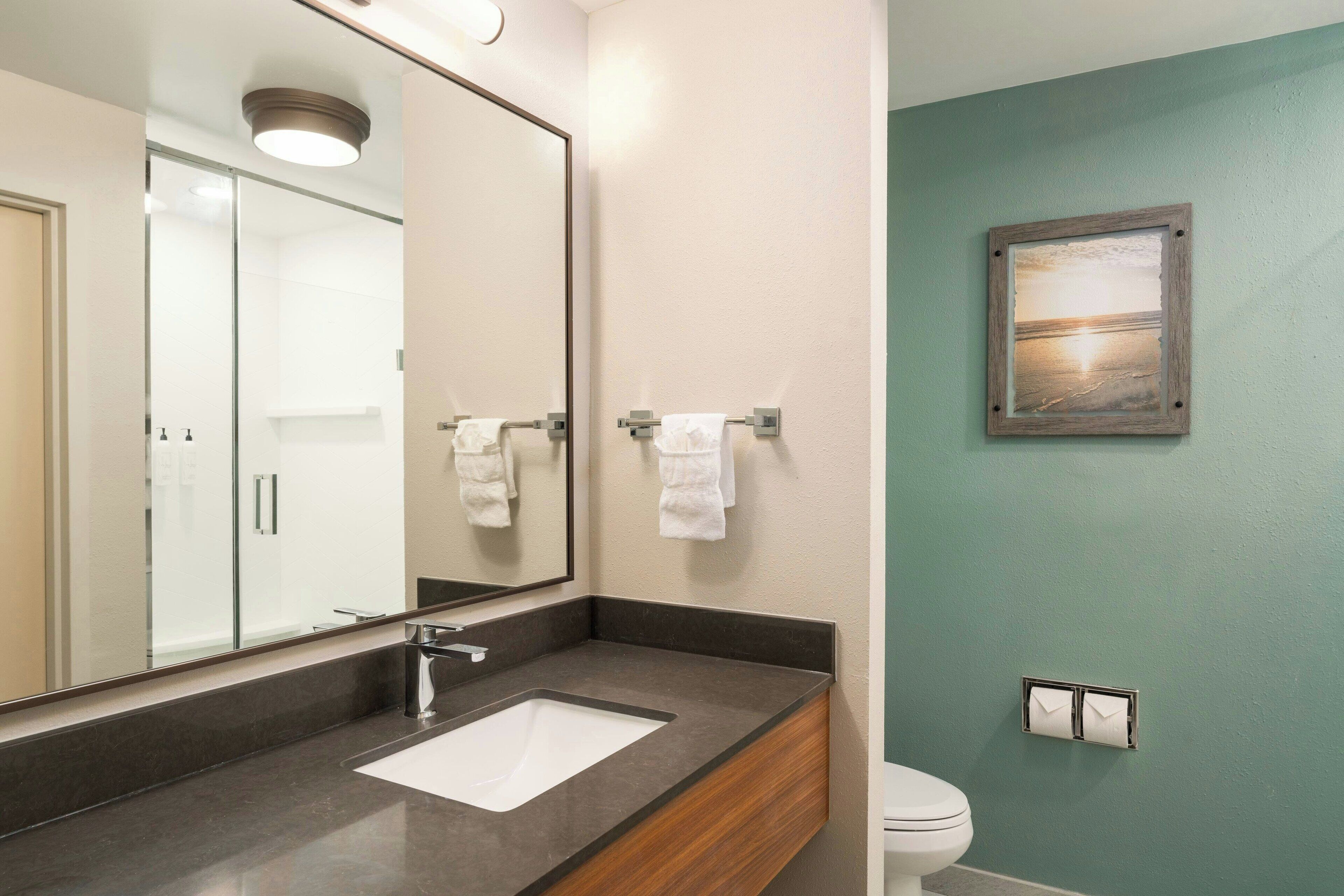 A bathroom with a large mirror, a sink, and a toilet.