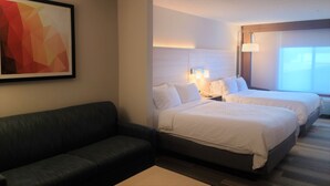 Une chambre d’hôtel avec deux lits, un canapé, un bureau et un tableau au mur.