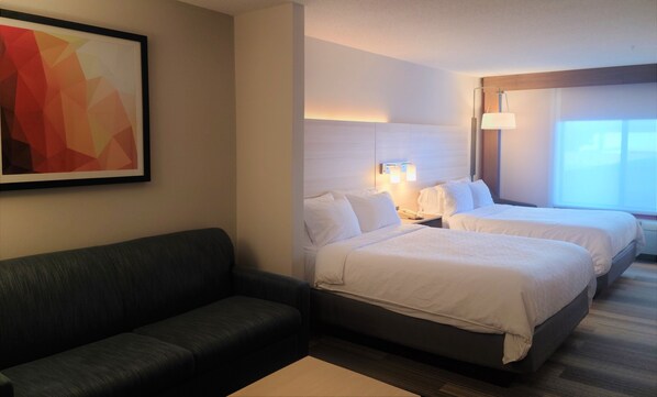 A hotel room with two beds, a sofa, a desk, and a painting on the wall. - Holiday Inn Express Newton Falls by IHG (Newton Falls)