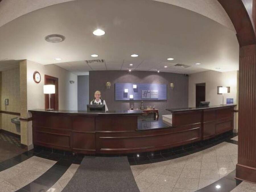 Un espace d’accueil d’hôtel comprenant un comptoir d’accueil incurvé, un réceptionniste et un bureau d’accueil.