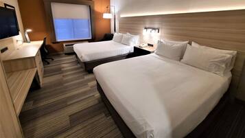 A hotel room with two beds, a desk, a chair, a TV, and a window with blinds.