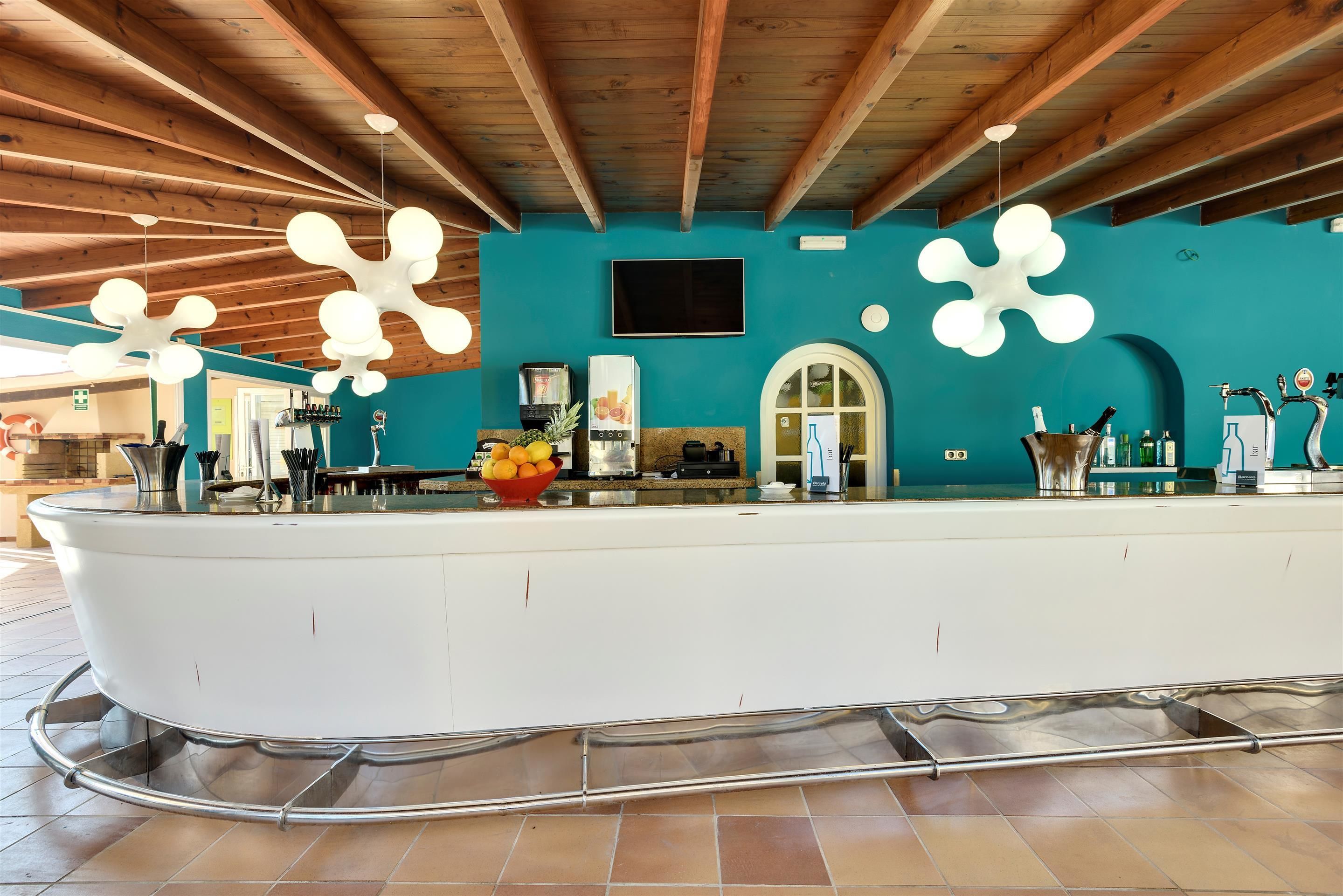 A modern kitchen with a central island, wooden ceiling beams, and a teal accent wall.