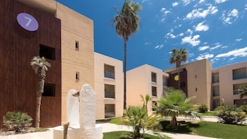 Un bâtiment moderne, orné d’un panneau portant le chiffre « 7 », entouré de palmiers et doté d’une pelouse bien entretenue.