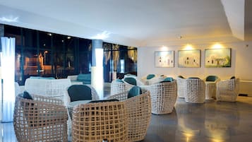 A spacious lobby with wicker furniture, large windows, and artwork on the walls.
