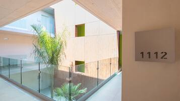 A modern interior with a glass railing, a potted plant, and a sign with the number 1112.
