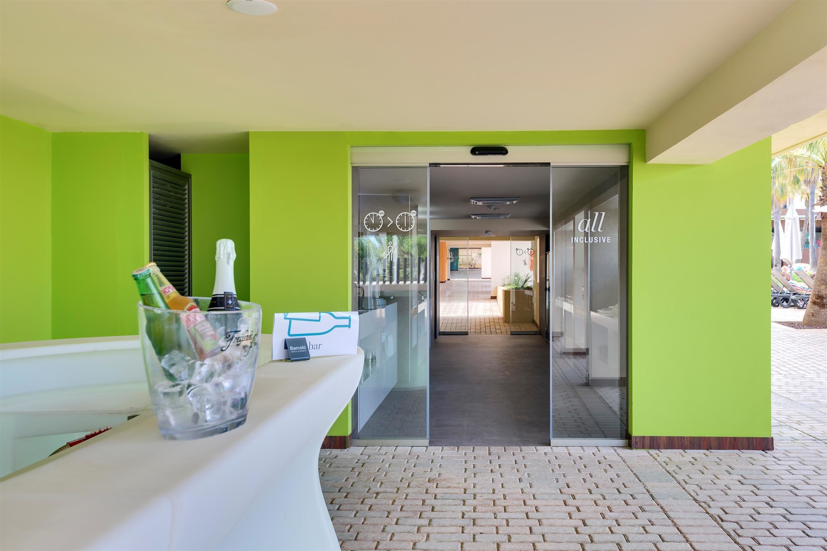 A reception area with a glass door, a reception desk, and a glass container with bottles.
