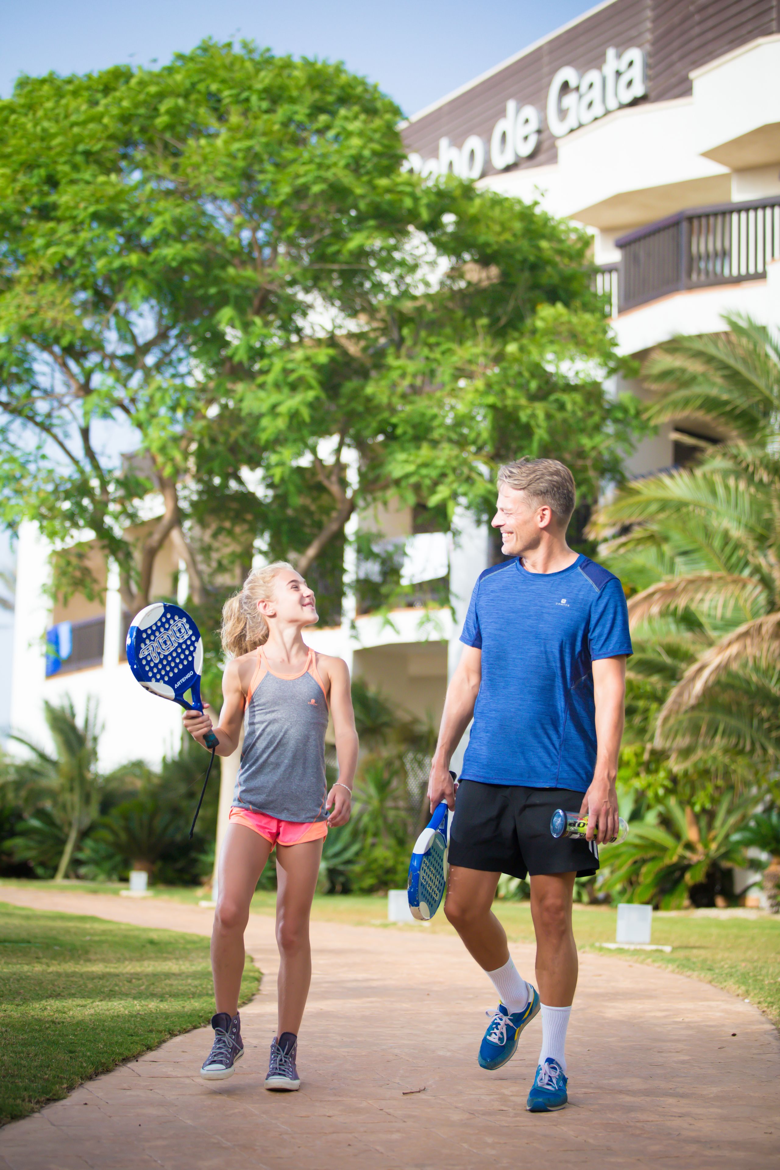 Two people walking on a pathway with a building in the background.