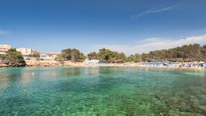 A beach with clear turquoise water, a sandy shore, and a row of beach umbrellas.
