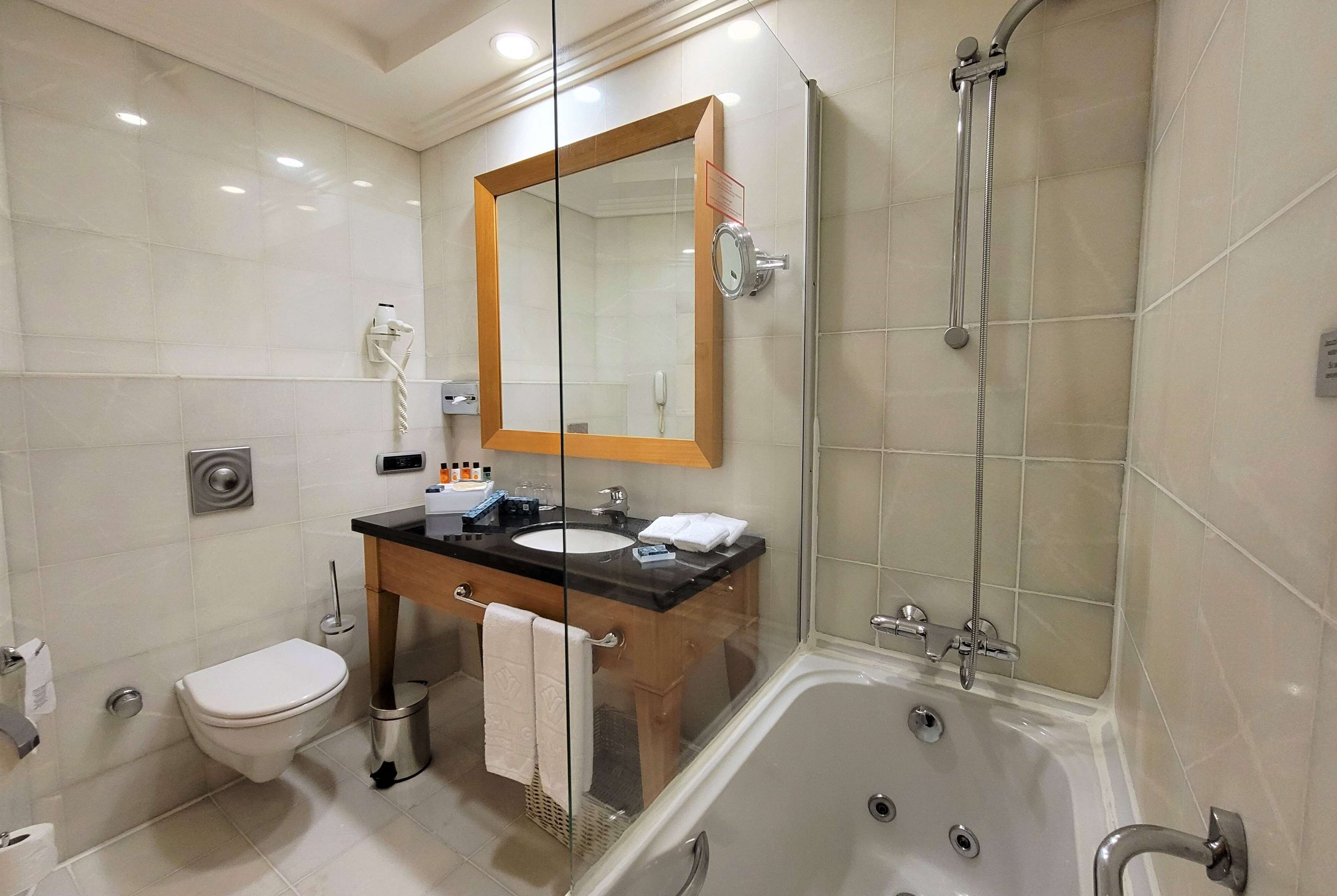 Un baño moderno con ducha de vidrio, bañera, inodoro y tocador con espejo.