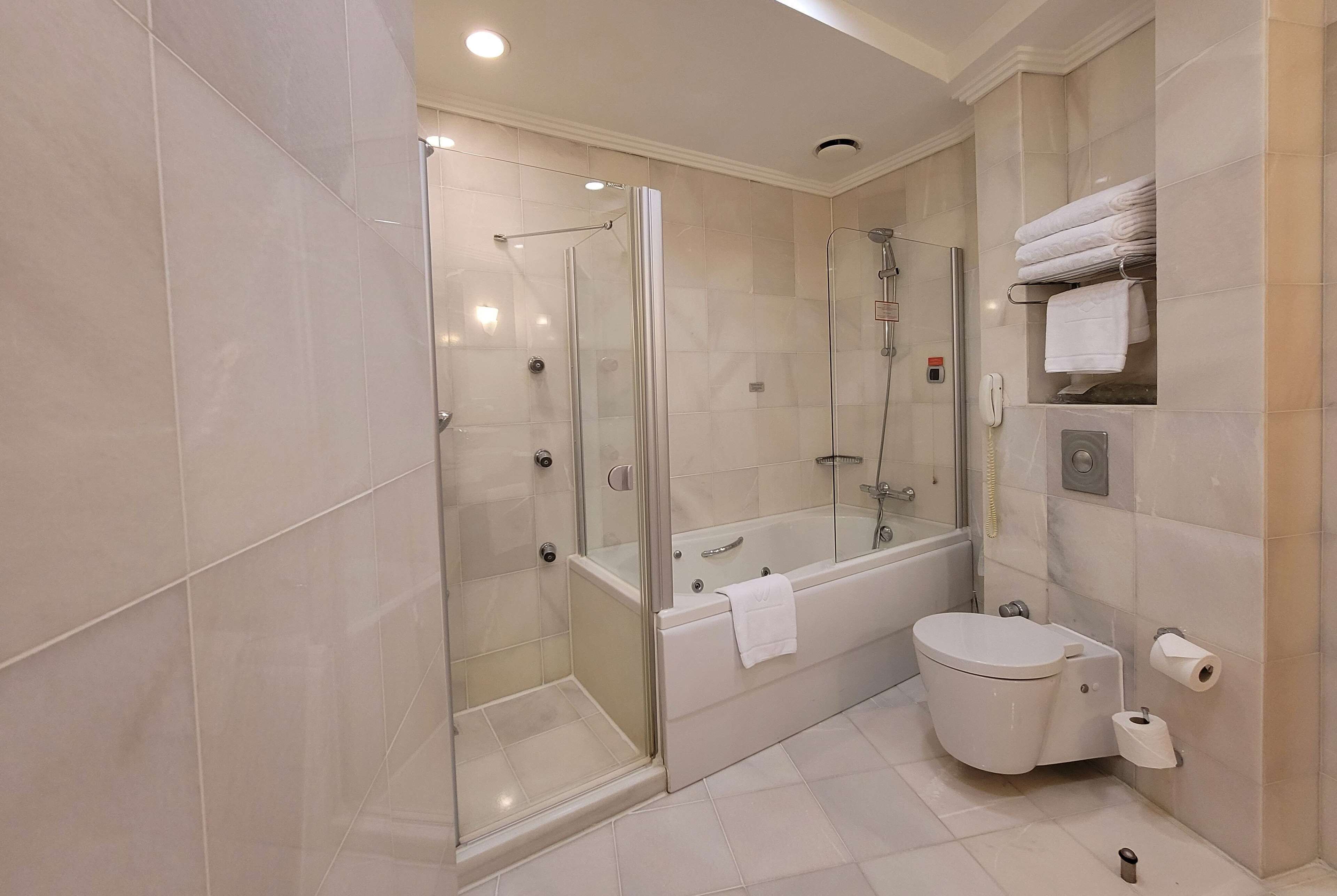 A modern bathroom with a glass-enclosed shower, a bathtub, and a toilet.