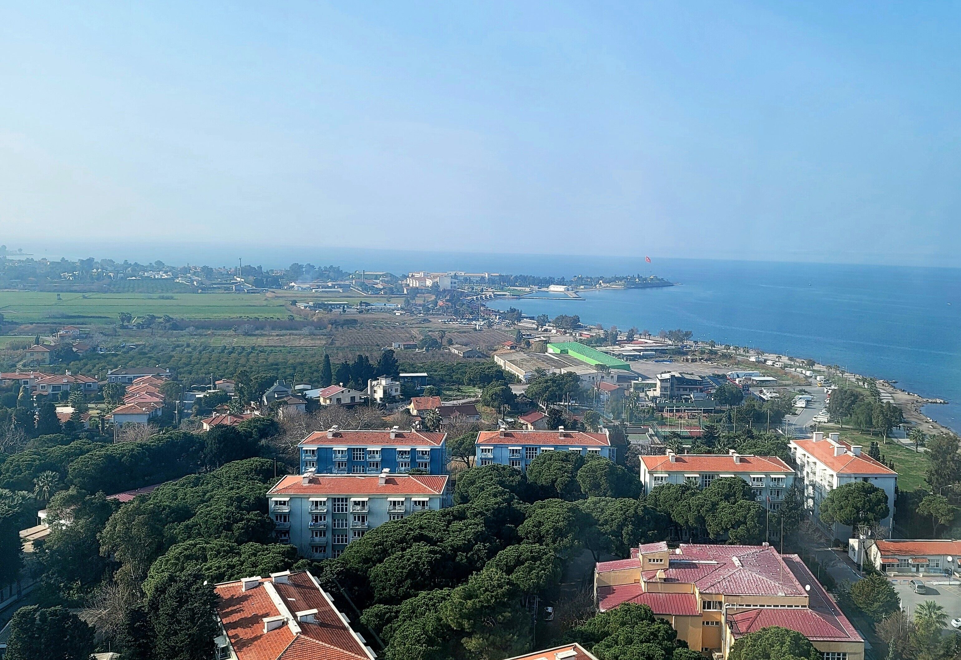 Un pueblo costero con edificios residenciales, un puerto deportivo y una vista despejada del mar.