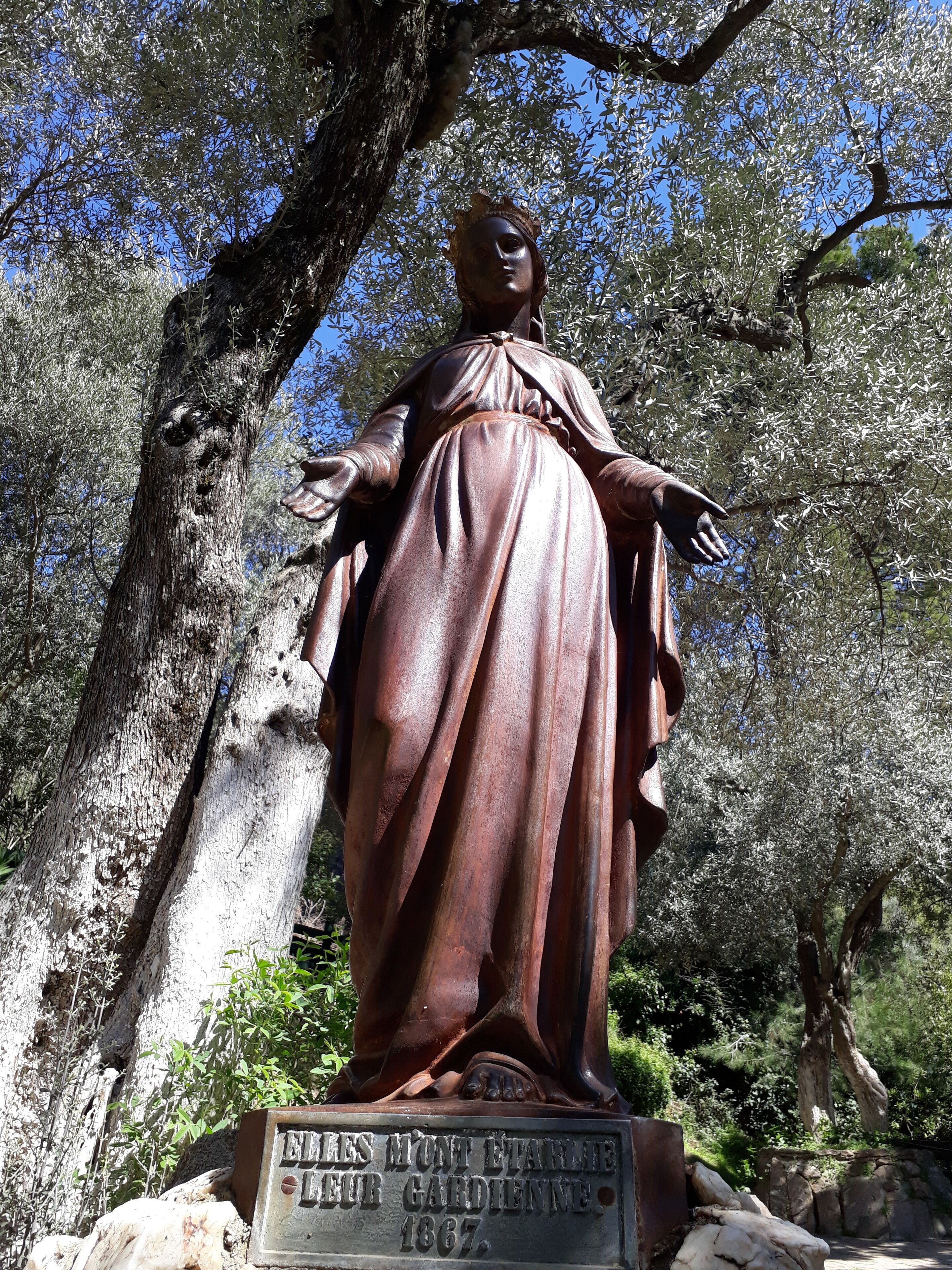 A statue of a woman with a long robe, standing on a pedestal with a plaque.