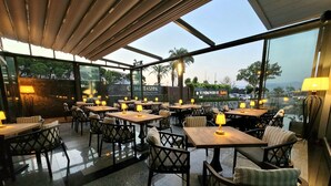 Een restaurant met terras, tafels met lampen en uitzicht op de stad.