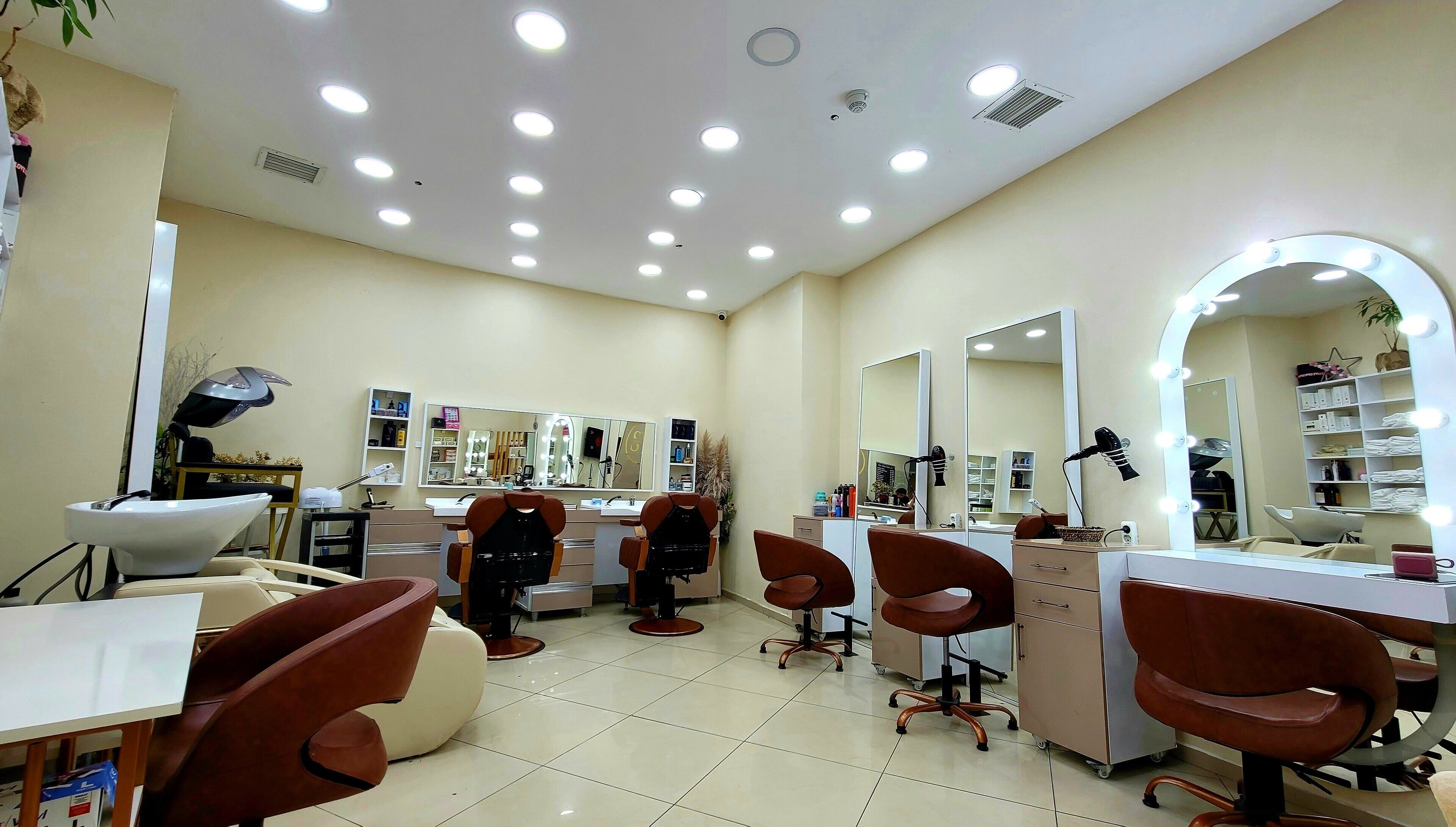 A well-lit salon with multiple mirrors, chairs, and a vanity area.