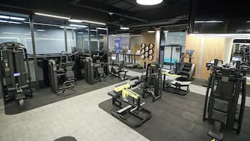 Un gimnasio con diferentes máquinas de ejercicio, cintas de correr y equipo de levantamiento de pesas.
