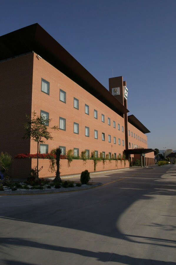 A multi-story hotel with a brick facade, multiple windows, and a sign indicating it is a hotel. - Hotel Posadas de España Málaga (Málaga)