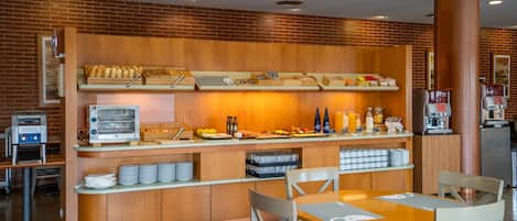 A breakfast bar with a variety of food items, a coffee machine, and seating arrangements.