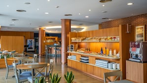 A modern hotel lobby with a coffee bar, seating area, and a vending machine.