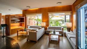 A modern hotel lobby with wooden paneling, comfortable seating, and large windows offering a view of the outdoors.