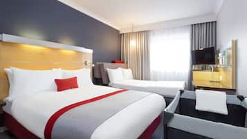 Een hotelkamer met een groot bed, een kleiner bed, een bureau met stoel, een televisie en een badgedeelte.