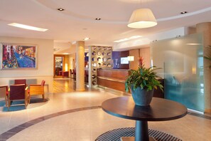 Eine Hotelhalle mit einer Rezeption, einer Sitzecke und einem großen Gemälde an der Wand.