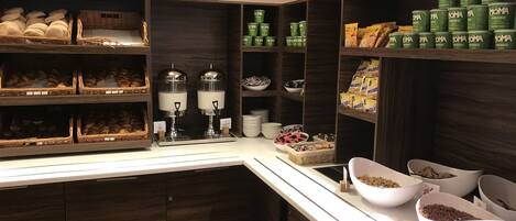Zona de desayuno tipo buffet con diversas opciones de comida y bebidas.