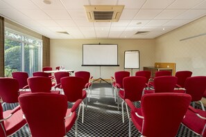 A conference room with red chairs arranged in rows, a whiteboard, and a projector screen. - Holiday Inn Express Southampton M27 Jct7 by IHG (Southampton)