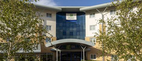 A Holiday Inn Express building with a modern architectural design, featuring a large glass facade and a covered entrance area.