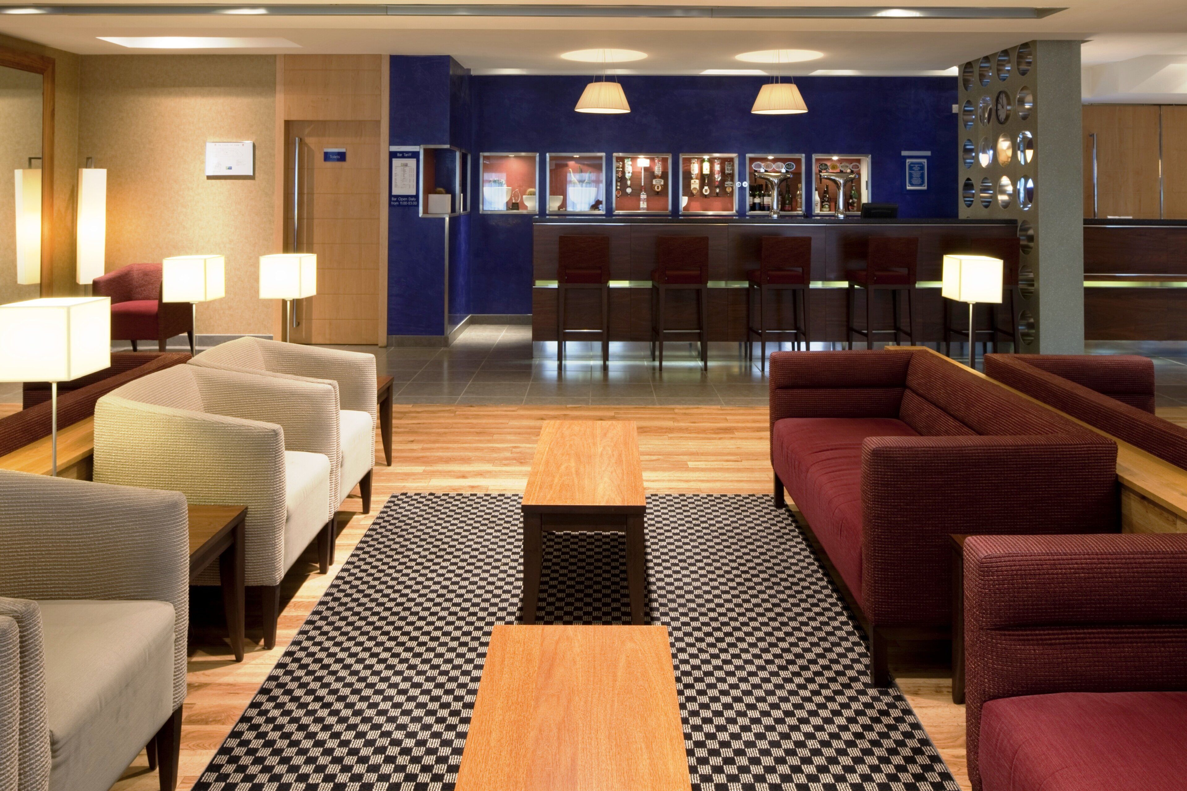 A hotel lobby with seating areas, a reception desk, and a bar.