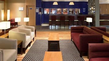Un vestíbulo de hotel con zonas de estar, una recepción y un bar.