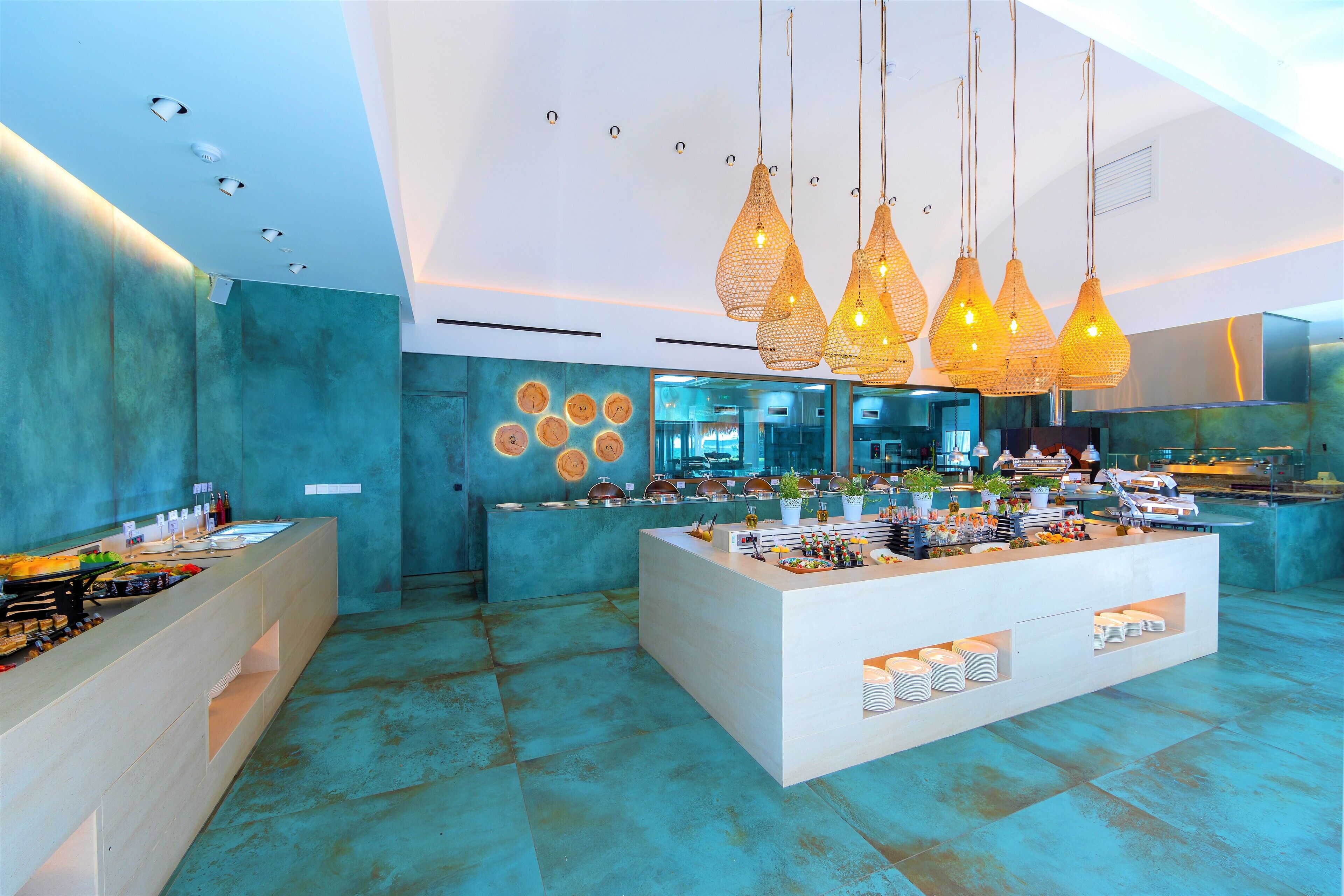 A modern kitchen with a central island, pendant lights, and a teal-colored backsplash.