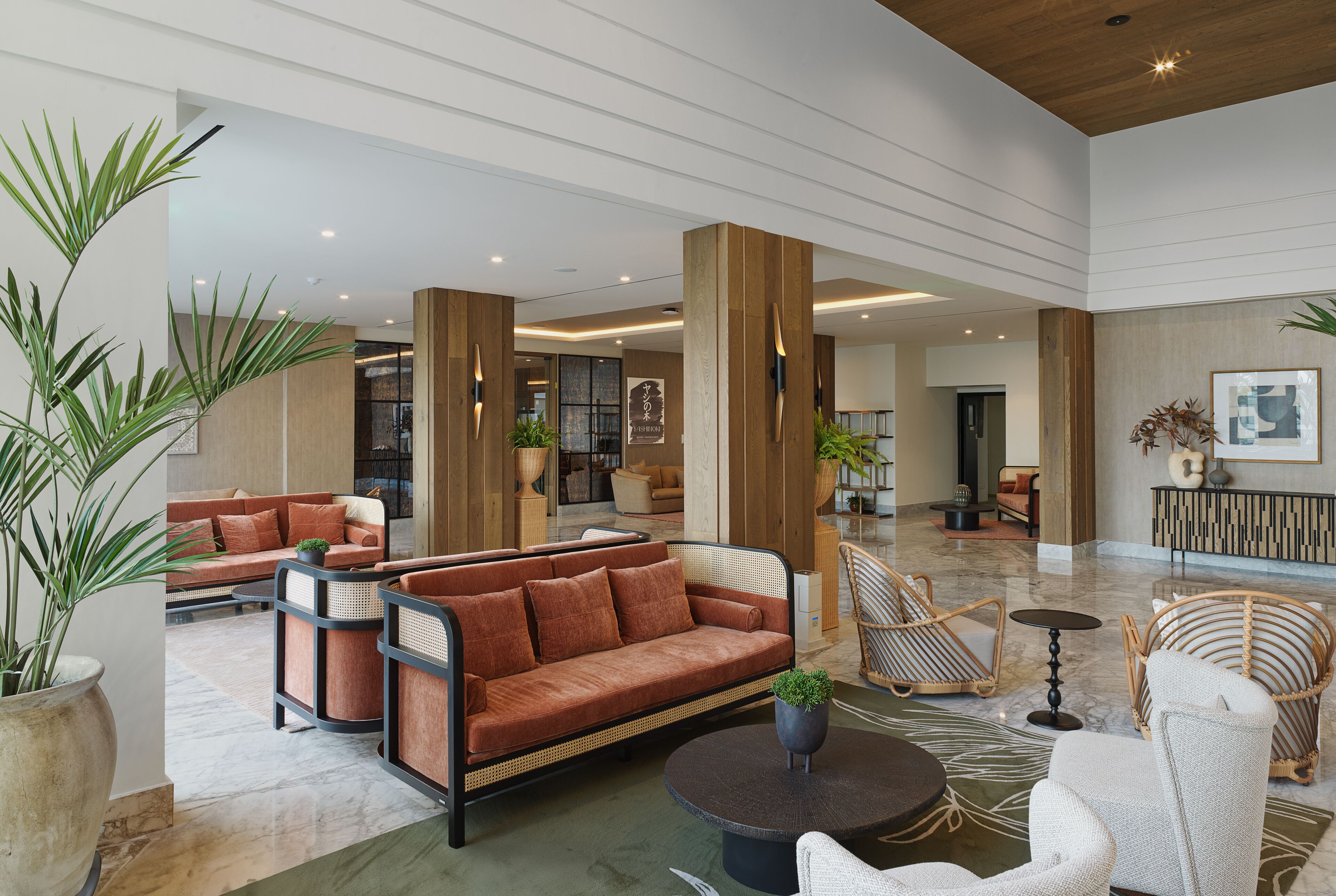 A spacious lobby with a large sofa, wicker chairs, and a coffee table.