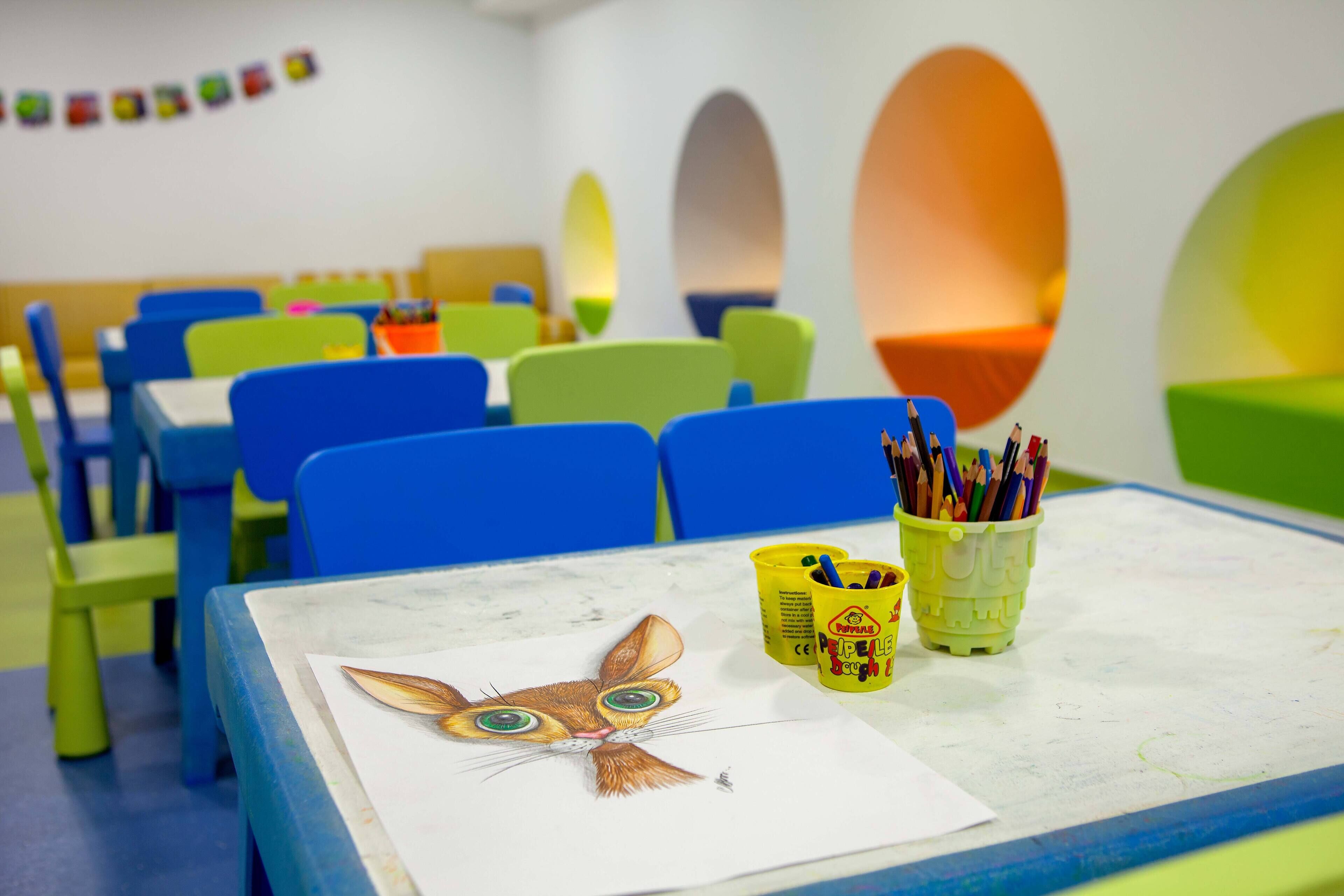 A classroom with colorful chairs, tables, and educational materials.