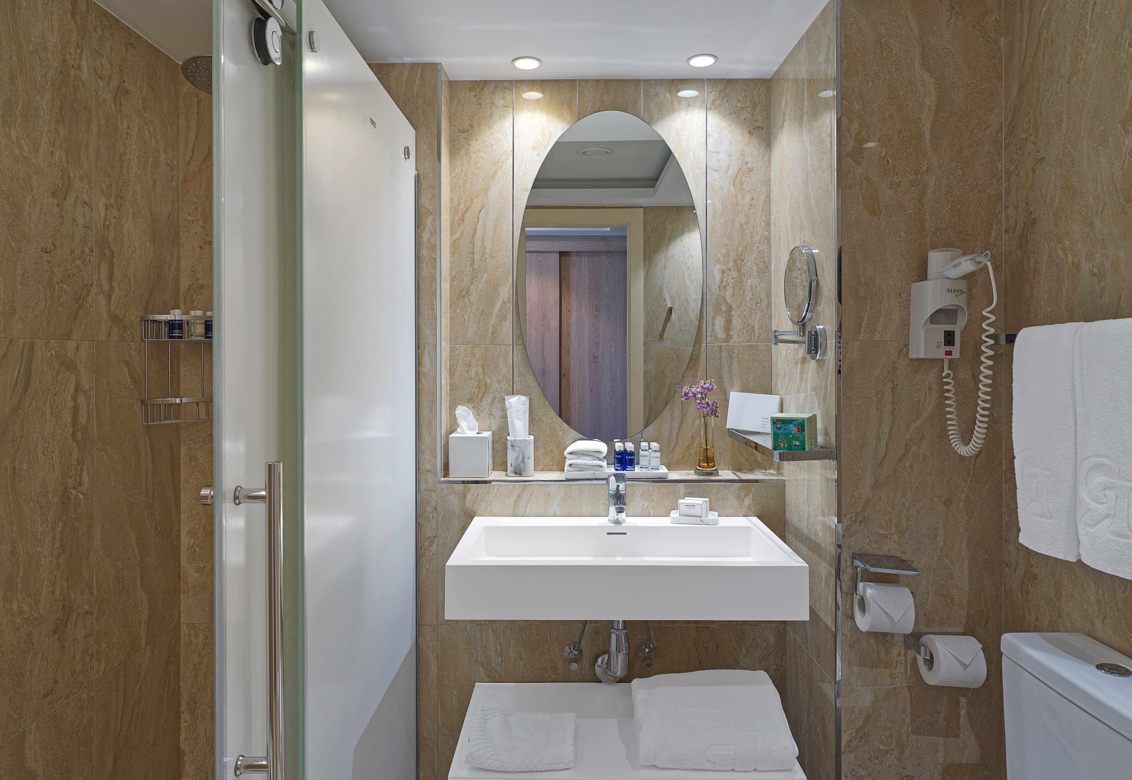 Un baño con un lavabo blanco, un espejo, un toallero y un inodoro.