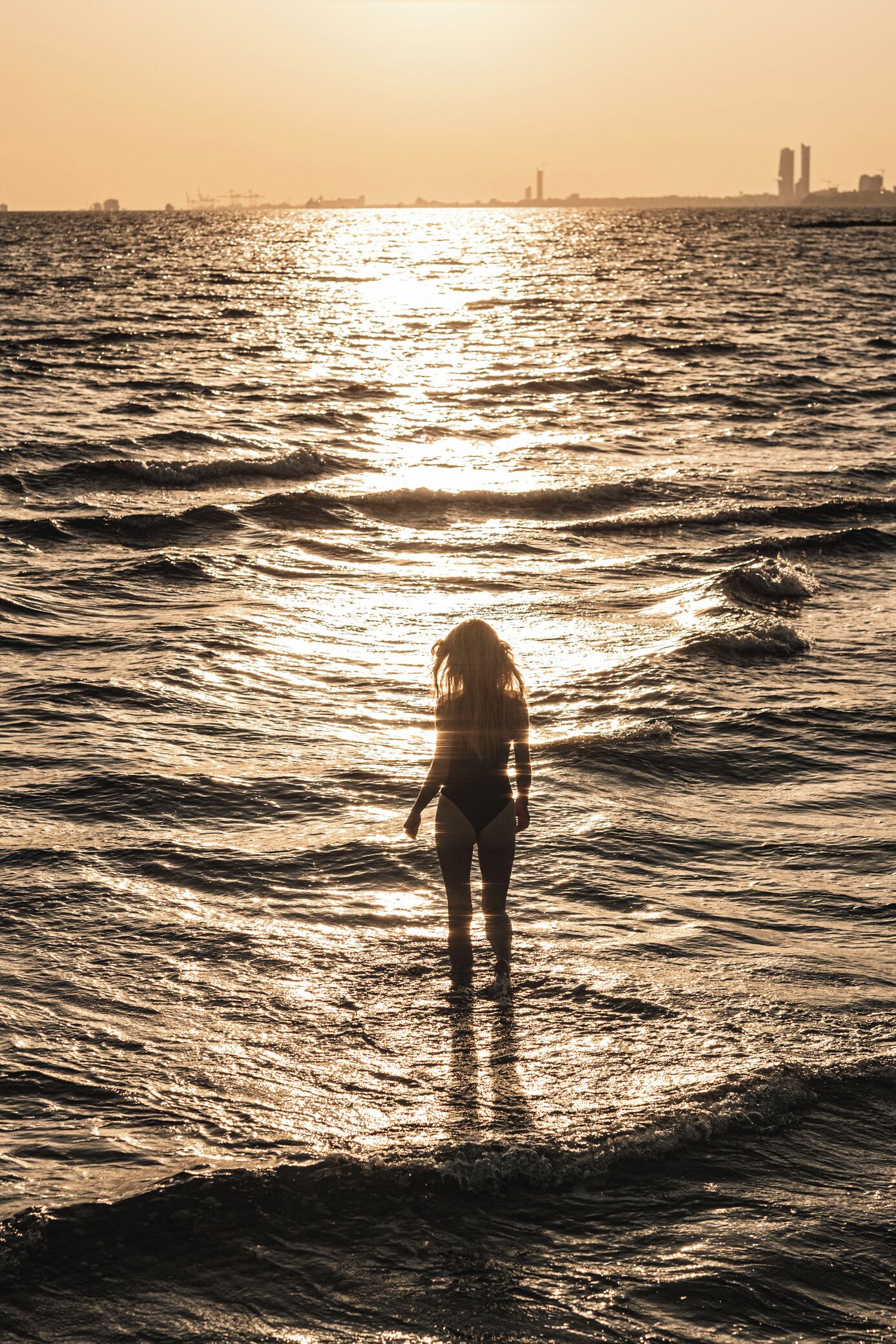 Una persona de pie en el agua al atardecer.