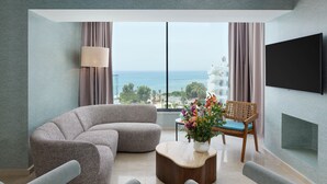 Ein modernes Wohnzimmer mit einer gebogenen Couch, einem Holztisch und Meerblick durch große Fenster.