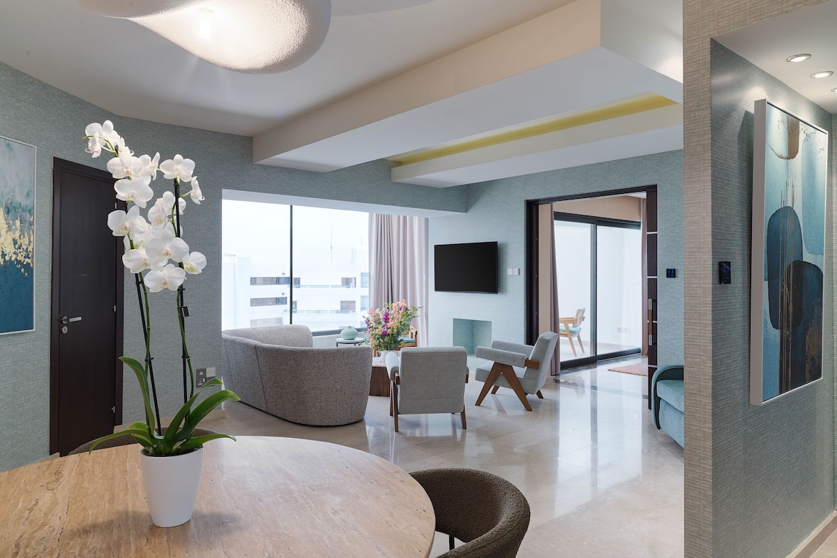 A modern living room with a round table, a potted orchid, and a sofa.