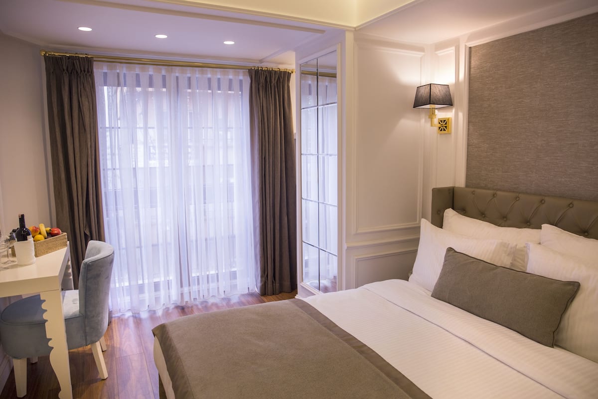 Habitación de hotel con una cama grande, un escritorio con silla y una ventana con cortinas.