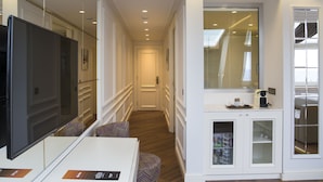 Un pasillo de hotel con televisor, zona de estar y kitchenette.