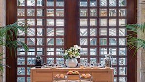 A breakfast setup with pastries, coffee, and a vase of flowers in front of a large window with a grid pattern. - Park Hyatt Milano (Milan)