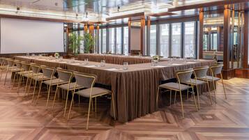 A conference room with a long table, chairs, and a projector screen.