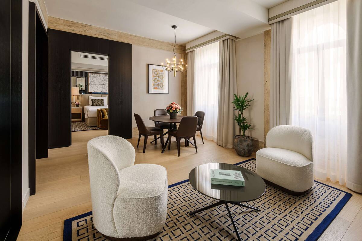 A modern living room with a dining area, a sofa, a coffee table, and a potted plant.