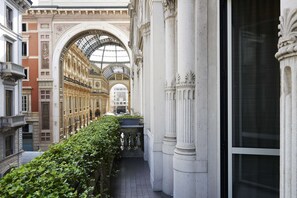 Un estrecho pasillo con columnas ornamentales y un techo de cristal, que conduce a un edificio imponente de arquitectura clásica.