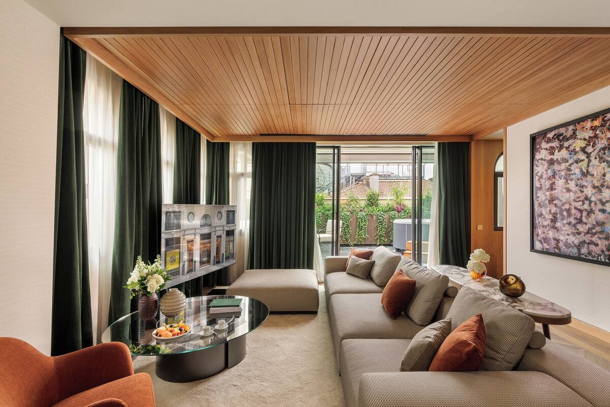 A modern living room with a sofa set, a glass coffee table, and a bookshelf.
