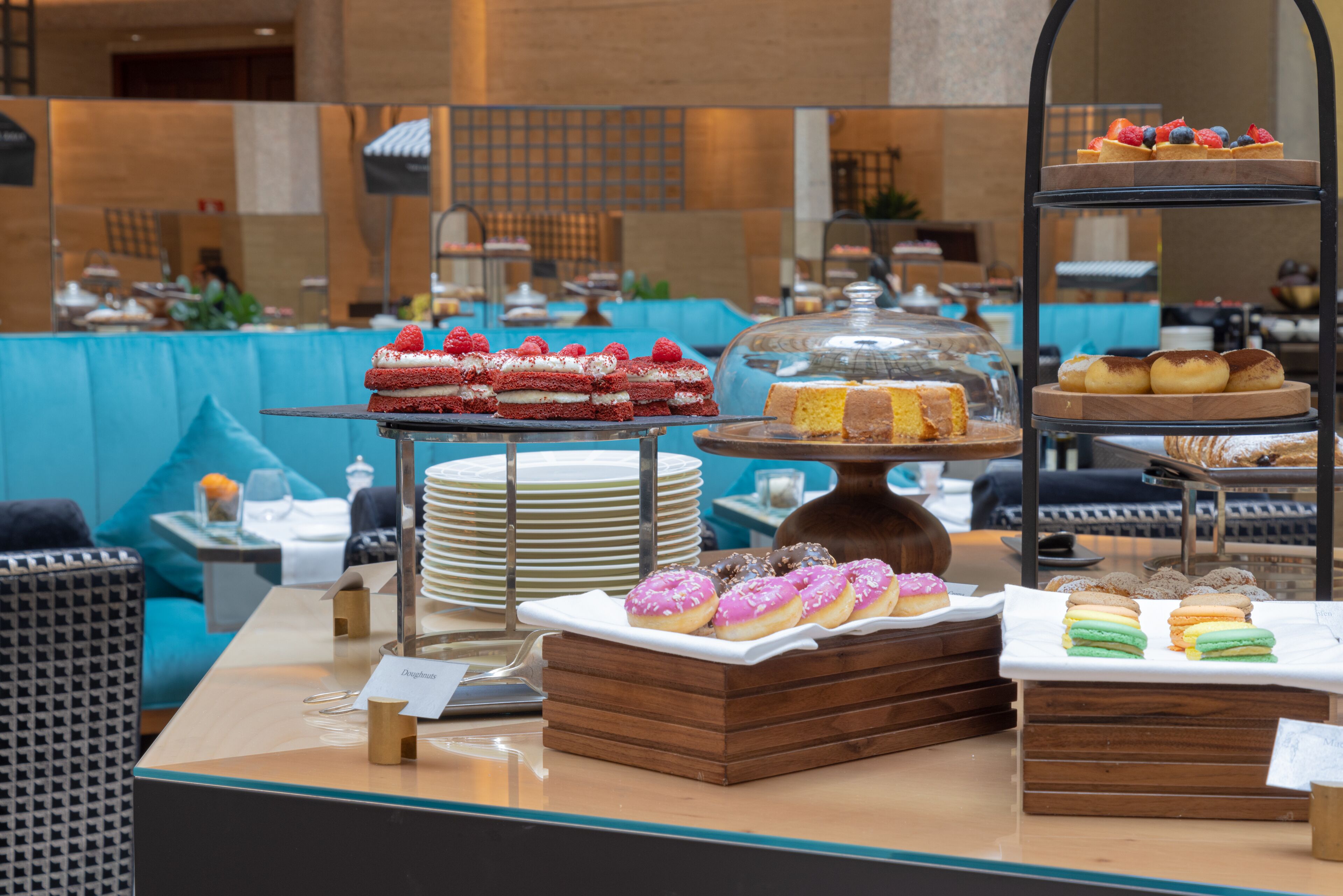 Een buffet met diverse desserts en gebak, waaronder taarten, donuts en patisserie, gepresenteerd op etagères en schalen.