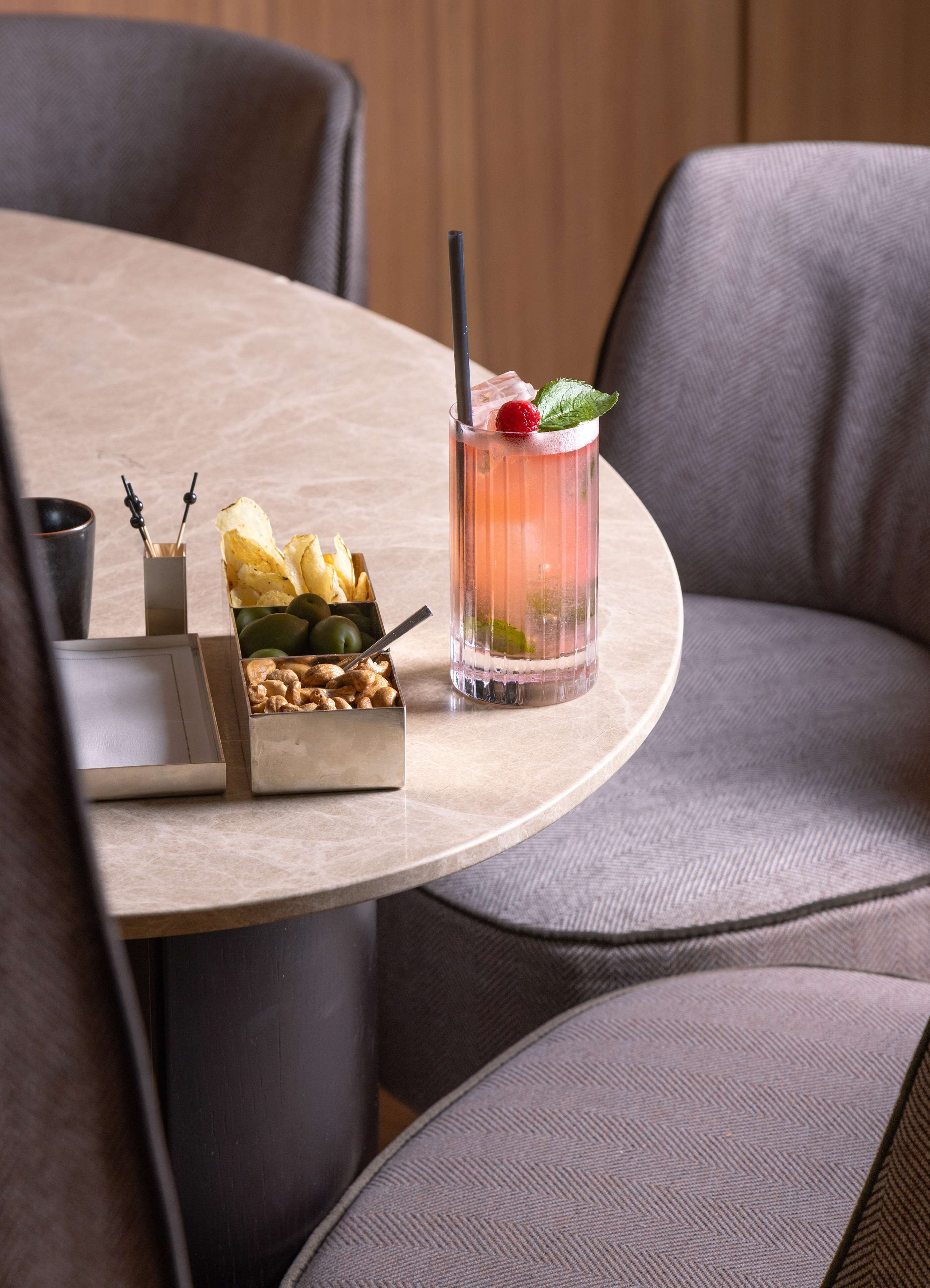 A round table with a drink, snacks, and a small box of chocolates.