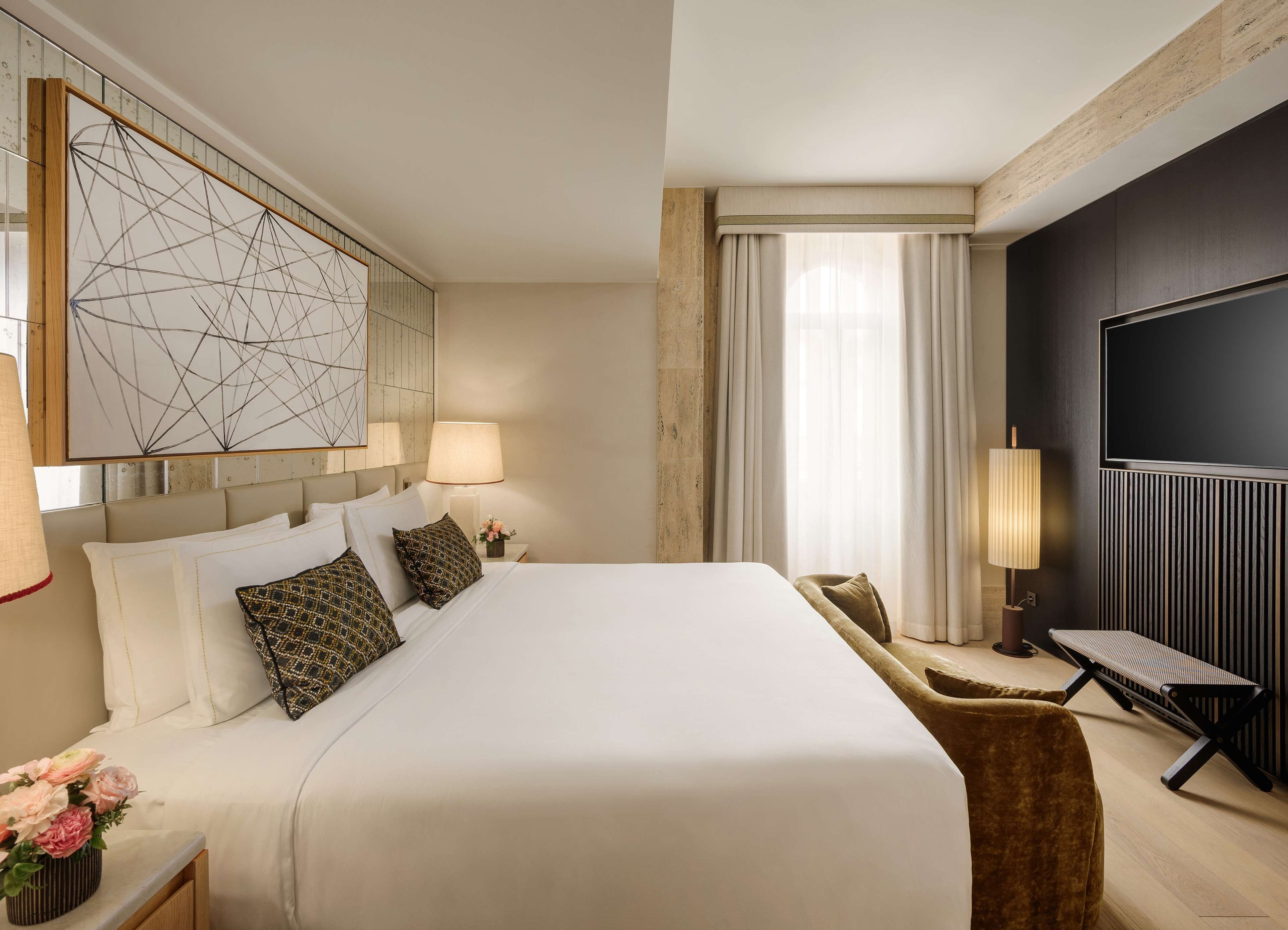A hotel room with a large bed, a flat-screen TV, a desk, and a modern art piece on the wall.