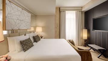 Ein Hotelzimmer mit einem großen Bett, einem Flachbildfernseher, einem Schreibtisch und einem modernen Kunstwerk an der Wand.