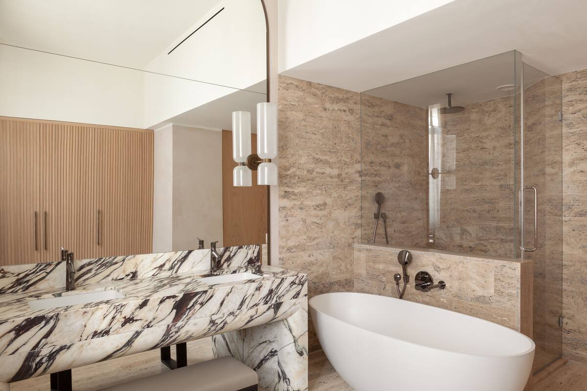 A modern bathroom with a freestanding bathtub, a marble vanity, and a glass-enclosed shower area.